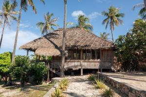a hut on the beach with palm trees at Rote Beach House in Nembrala