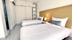two beds in a hotel room with white sheets at Azure apartahotel in Santa Marta
