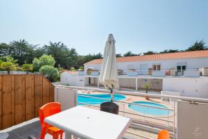 eine Villa mit Pool und einem Tisch mit Sonnenschirm in der Unterkunft Resid Azur in Saint-Jean-de-Monts