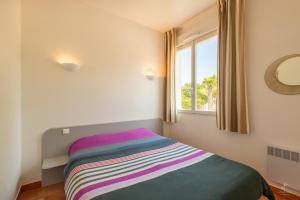 ein Bett in einem Zimmer mit Fenster in der Unterkunft Resid Azur in Saint-Jean-de-Monts