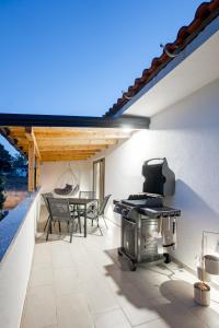 a patio with a grill and a table and chairs at Grgurić Apartments in Rab