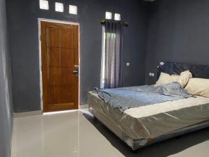 a bedroom with a bed and a wooden door at Andre Homestay in Kuta Lombok