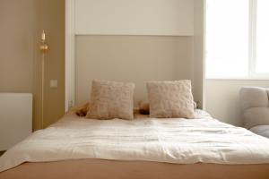 a bed with white sheets and pillows in a bedroom at Studio meublé Le Refuge doré avec Netflix in Homécourt