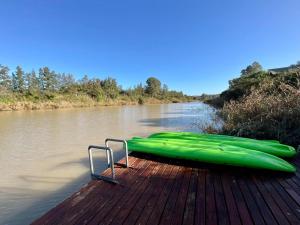 a green canoe sitting on a dock on a river at Ndlovu Addo River Lodge in Kirkwood +2 photos