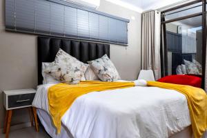 a bedroom with a bed with a yellow blanket on it at The Space Guesthouse Mondlo in Mondlo +111 photos