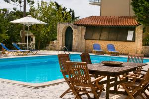 a wooden table and chairs next to a swimming pool at Irena Studios & Apartments in Sarláta