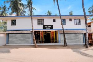 een wit gebouw met palmbomen ervoor bij Super Hotel O Calangute Beach St. Anthony's Chapel Formerly Hotel Sun & Sea in Goa