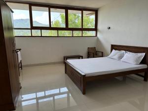 a bedroom with a bed and a large window at The Dee's at sinharaja in Rakwana