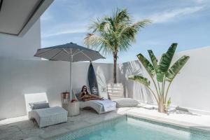 a woman sitting on a bed next to a swimming pool at Brand new Luxury 2 BR Villa CASA COCO LAUBANA in Uluwatu
