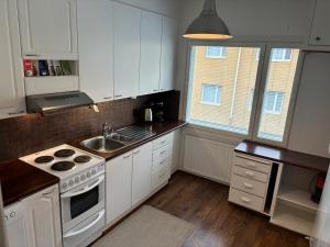a kitchen with white cabinets and a sink and a stove at Malmi Home in Vaasa +10 photos