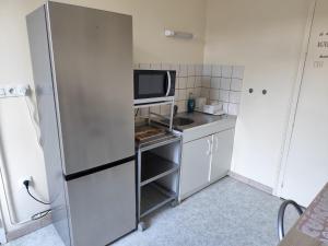 a small kitchen with a refrigerator and a microwave at Résidence de l'arc Terrasse in Bourbon-Lancy