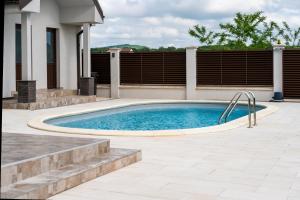 a swimming pool in a yard next to a house at Pensiunea JOY in Baile Felix