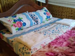 Una cama con mantas y almohadas coloridas. en Weaver Bird Hostel, en Rubanda