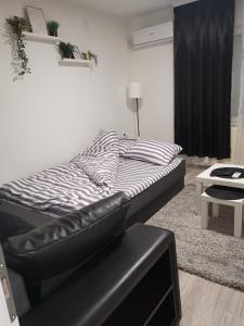 a bed in a room with a black and white comforter at Stan na dan Pozarevac Apartman Olja in Požarevac