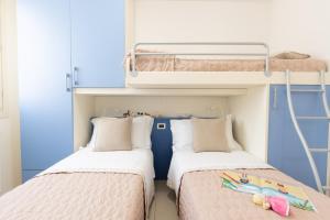 two beds in a room with two bunk beds at ANIMA JESOLO - DRAGO VILLAGE, Beach & Pool, 2 Parkings in Lido di Jesolo +201 photos