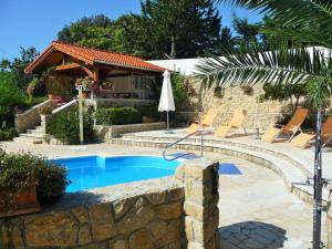 a pool with chairs and an umbrella next to a house at Apartments Angela in Kampor