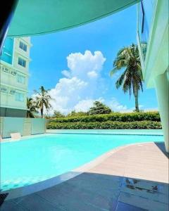 a swimming pool with palm trees and a building at Two Bedroom at One Spatial Iloilo in Iloilo City