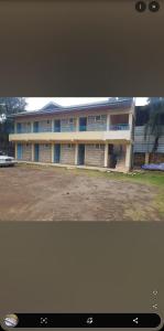a large white building with blue doors in a parking lot at Robeck's Guest House in Gatunga