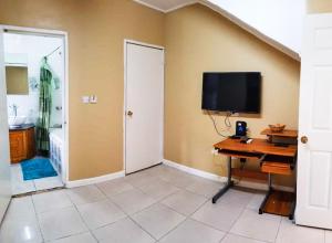 a room with a desk and a television on a wall at Candy's Palace Apartments -Dominica's Best Hilltop Haven in Portsmouth