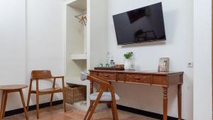 ein Schreibtisch mit einem Fernseher an einer Wand mit zwei Stühlen in der Unterkunft Padi Heritage Hotel in Karangjepun
