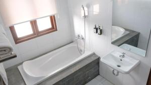 ein weißes Badezimmer mit Badewanne und Waschbecken in der Unterkunft Padi Heritage Hotel in Karangjepun + 20 Fotos