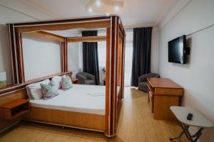 a hotel room with a canopy bed and a desk at Vila Dealul Sasului in Dâmbovicioara