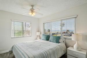a bedroom with a bed with a ceiling fan and windows at Beautiful 2 Bed Beach Condo #201 in Carpinteria +22 photos