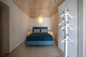 een slaapkamer met een blauw bed en witte muren bij Aria di Ceglie authentic elegance in Ceglie Messapica