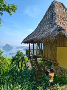 a hut with a thatched roof and a staircase at Elang Hillside Bamboo Villas in Labuan Bajo
