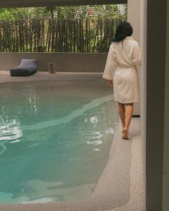 a woman looking out of a window at a swimming pool at Gerakas Belvedere Hotel & Spa in Vasilikos