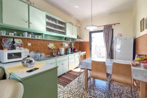 Una cocina con gabinetes verdes, una mesa y un refrigerador. en Giorgos House, en Nafpaktos