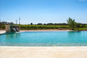 a swimming pool with a water fountain in a field at Agriturismo Tenuta Kyrios con piscina in Borgagne
