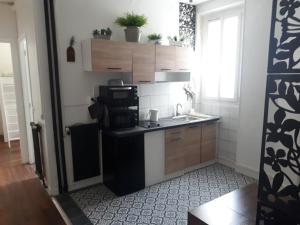 eine kleine Küche mit Spüle und Mikrowelle in der Unterkunft Vincennes - Parisian appartment in Vincennes