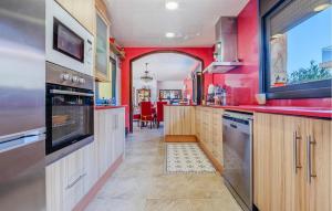 a kitchen with red walls and wooden cabinets at Pet Friendly Home In Segur De Calafell in Segur de Calafell