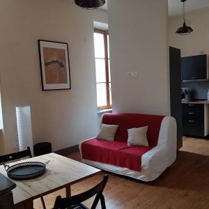 ein Wohnzimmer mit einem roten Sofa und einem Tisch in der Unterkunft Gîte de la tour avec piscine entre Carcassonne et narbonne in Capendu
