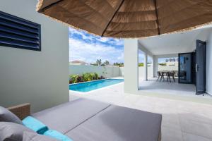 een woonkamer met een bank en een zwembad bij Villa Kura Cura - 5 Minutes From Mambo Beach in Willemstad