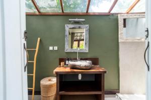 Un baño con lavabo y espejo en una pared verde. en Villa Maiya, en Gili Air