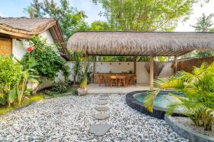 a patio with a table and a thatch roof at Villa Maiya - Charming 1-Bedroom Villa with Pool in Gili Islands