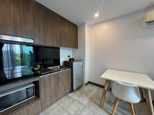 Una pequeña cocina con una mesa y un refrigerador. en Modern Naiharn Beach Duplex Apartment, en Rawai Beach