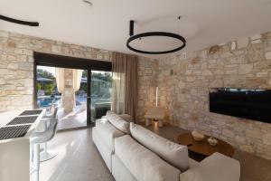 a living room with a white couch and a stone wall at Olive Residence in Skala Fourkas