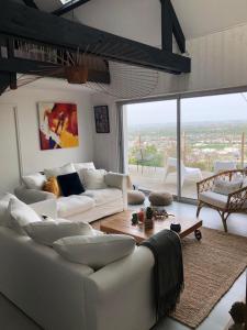 un soggiorno con mobili bianchi e una grande finestra di Cottage vue panoramique Pau Piscine a Laroin