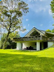 ein weißes Haus mit einer Terrasse auf einem Rasen in der Unterkunft Riverside Avrig in Avrig