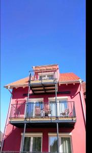 a red building with balconies and chairs on it at Casa Helvetia in Rheinhausen