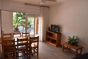 Un comedor con mesa y sillas y un televisor. en Apartamentos Les Palmeres, en Platja d'Aro