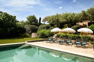 a pool with chairs and umbrellas in a yard at Auberge de l'Oumède in Saint-Tropez