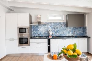 a kitchen with white cabinets and a bowl of fruit at Da Felicia in Capo dʼOrlando