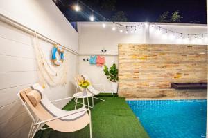 a room with a pool and two chairs and a table at Phirom2 pool villa pattaya in Jomtien Beach