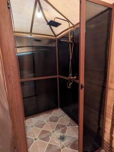 a shower with a glass door and a tiled floor at Desert Nights Camp in Merzouga