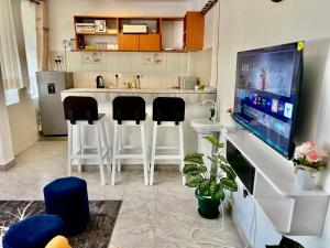 a kitchen with a bar with stools and a tv at Roje's Oasis in Jinja