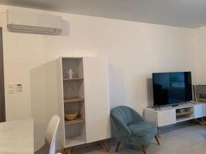 a living room with a blue chair and a tv at Splendide T3 neuf au bord de la plage in Propriano +6 photos